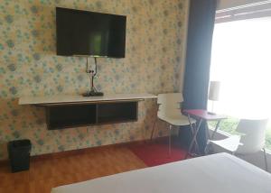 een kamer met een televisie aan een muur met een tafel en stoelen bij The Ring Khokmao Hotel 