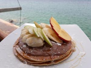 a stack of pancakes with chocolate and apples on a plate at ARTEMIS ROOMS in Pefki