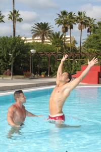 two men are standing in a swimming pool at Bungalows Artemisa Gay Men Only in Playa del Ingles