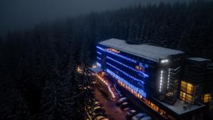 nocny widok na budynek z niebieskimi światłami w obiekcie Hotel Cindrel w mieście Păltiniş