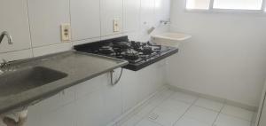 uma cozinha branca com um fogão e um lavatório em Apartamento Bem Viver em Salvador