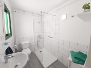 a white bathroom with a toilet and a sink at Apartamento Mar y Sol Tamaduste con terracita y barbacoa a 12 metros del mar in Tamaduste