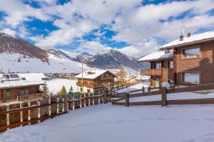 un lodge en la nieve con montañas en el fondo en Casa Luminosa Ski in -Ski out 100m - Happy Rentals en Livigno