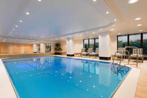 a large swimming pool in a hotel with chairs and tables at Maritim Hotel Am Schlossgarten in Fulda