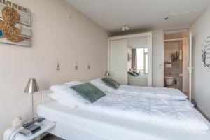 a white bedroom with a large white bed at Appartementencomplex Juliana 114 in De Koog