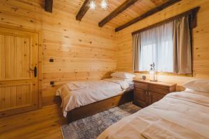 a bedroom with two beds in a log cabin at Eco Village & Chalets Green Heaven in Mojkovac