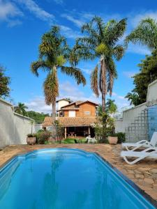 a house with a swimming pool and palm trees at Woods Hostel in Belo Horizonte