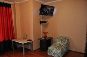 um quarto com uma cadeira e uma televisão na parede em Spacious apartment with balcony em Kremenchuk