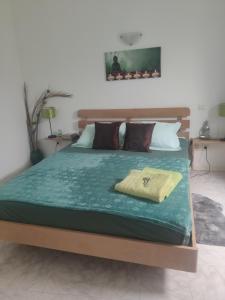 a bed with a green comforter on top of it at Maderalzinho in Mindelo