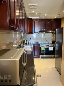 a kitchen with wooden cabinets and a black refrigerator at Royal Breeze view in Ras al Khaimah