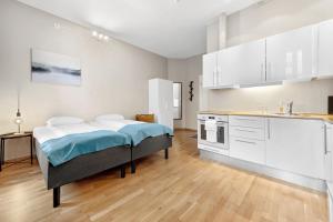 a bedroom with a bed and a kitchen with white cabinets at Forenom Serviced Apartments Oslo Nobel in Oslo
