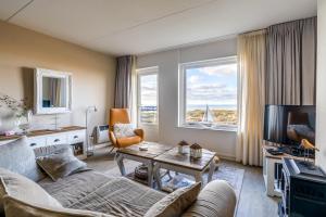 ein Wohnzimmer mit einem Sofa, einem Tisch und einem TV in der Unterkunft Appartementencomplex Juliana 116 in De Koog