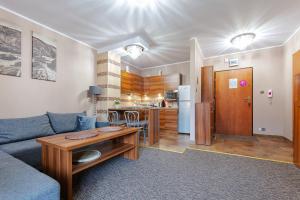 シュクラルスカ・ポレンバにあるVacationClub – Osiedle Podgórze 1C Apartament 5のリビングルーム(ソファ、テーブル付)、キッチンが備わります。