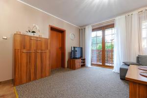 een woonkamer met een bank en een televisie bij VacationClub – Osiedle Podgórze 1C Apartament 5 in Szklarska Poręba