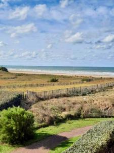 a fence on the beach with the ocean in the background at Cabourg-La mer à vos pieds et la thalasso à 50 m in Cabourg