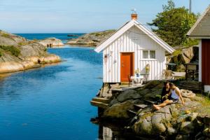 two people sitting on a rock in front of a small house at Portør Pensjonat in Kragerø