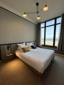 um quarto com uma cama grande e uma janela grande em L'Échappée - Hôtel Casino Dieppe em Dieppe