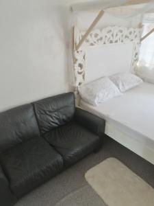 un sofá de cuero negro sentado junto a una cama en Golden Nest en Mombasa