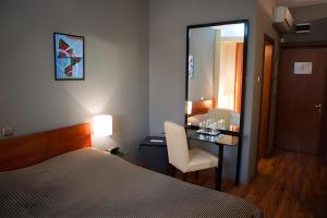 a bedroom with a bed and a desk with a mirror at Tania-Frankfurt Hotel in Bucharest