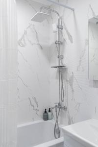 a shower in a white bathroom with a sink at RentWill apartments Oliva in Chişinău