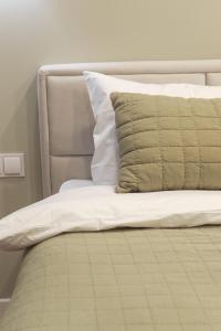 a bed with white sheets and a green pillow at RentWill apartments Oliva in Chişinău