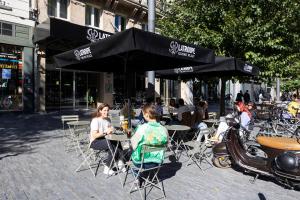 a group of people sitting at tables with umbrellas at LATROUPE Grand Place Hostel in Brussels