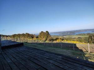 a wooden deck with a view of a field at Agradable y cómoda cabaña con vista espectacular in Chonchi