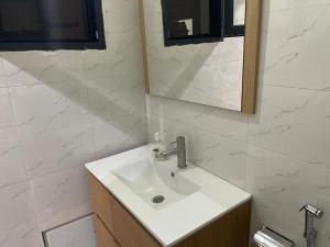 a bathroom with a white sink and a mirror at F2 tout confort au Point E Dakar ! in Dakar +2 photos