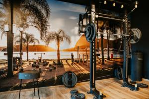 a gym with a view of the water and palm trees at Rioca Neu-Ulm Posto 5 in Neu-Ulm