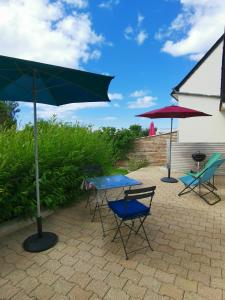 drie tafels en stoelen met parasols op een patio bij Ty Bian, à la campagne et proche de la plage in Le Conquet