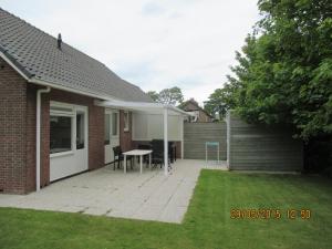 a house with a patio with a table and a fence at Jadi in Cadzand