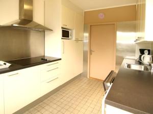 a kitchen with white cabinets and a black counter top at Jadi in Cadzand