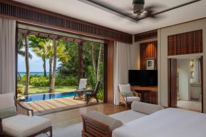 Schlafzimmer mit einem Bett und Poolblick in der Unterkunft Anantara Maia Seychelles Villas in Anse Boileau