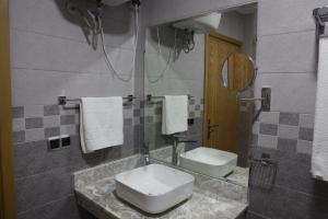 een badkamer met een wastafel, een toilet en een spiegel bij RESIDENCE CENTROSUIT in Laayoune