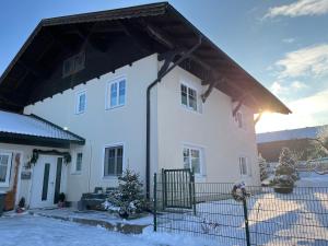 a white house with a black roof in the snow at Pferdehof Thomayer in Strasswalchen