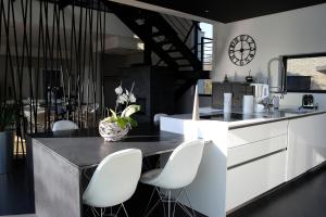 eine Küche mit weißen Stühlen und einer Theke mit einer Uhr in der Unterkunft Luxueux Domaine Dal Cayrou grande piscine Cahors in Cahors