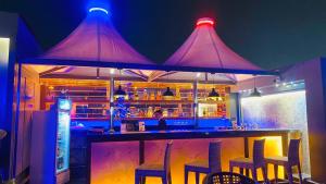 a bar with purple lights above a bar with stools at HoTeL TRENOR in Zirakpur