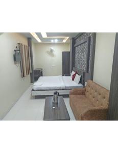 a bedroom with a bed and a couch and a table at Hotel New Grand, Deoghar in Deoghar