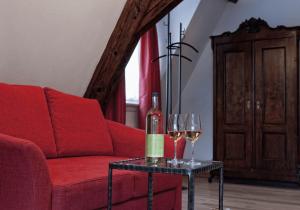 a red couch with a bottle and two glasses on a table at Gasthof zum Schwan in Sommerach