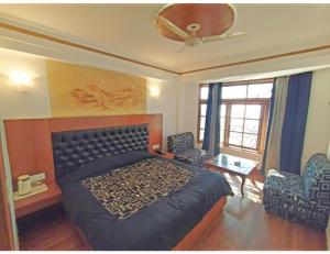 a bedroom with a bed and a ceiling fan at Hotel Horizon Picture Palace, Mussoorie in Mussoorie