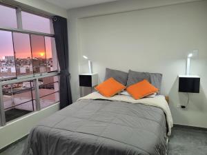 ein Schlafzimmer mit einem Bett mit orangefarbenen Kissen und einem Fenster in der Unterkunft Apartamentos "APPART D'ELIETTE" in Trujillo
