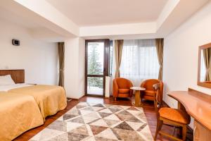 a hotel room with a bed and a desk and chairs at Hotel Cindrel in Păltiniş