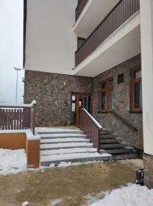 a stone building with stairs in the snow at Ski Apartmán Sajmon so saunou in Makov