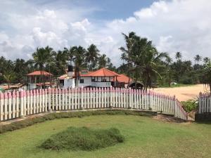 a white picket fence in front of a house at White VIlla Resort in Ahungalla