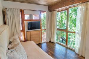 a living room with a television and large windows at Terrazas del Bosque Aparts in Mar de las Pampas