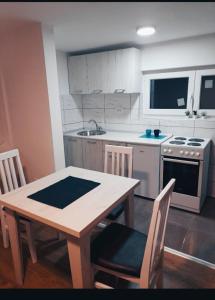 a kitchen with a wooden table with chairs and a stove at Apartmani Mir A1 in Vrnjačka Banja