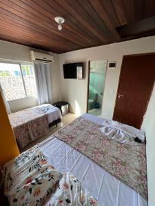 a hotel room with two beds and a window at Pousada Mar do Sonho Praia in Ipojuca