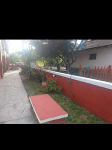 un banco rojo sentado en el césped junto a un edificio en Maria en Villa Gesell