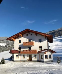 a large building with a balcony in the snow at Bio Schartenhof in Sankt Johann im Pongau