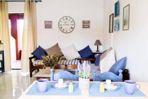 a living room with a couch and a clock on the wall at LEFKES Apartments Sidari in Sidari